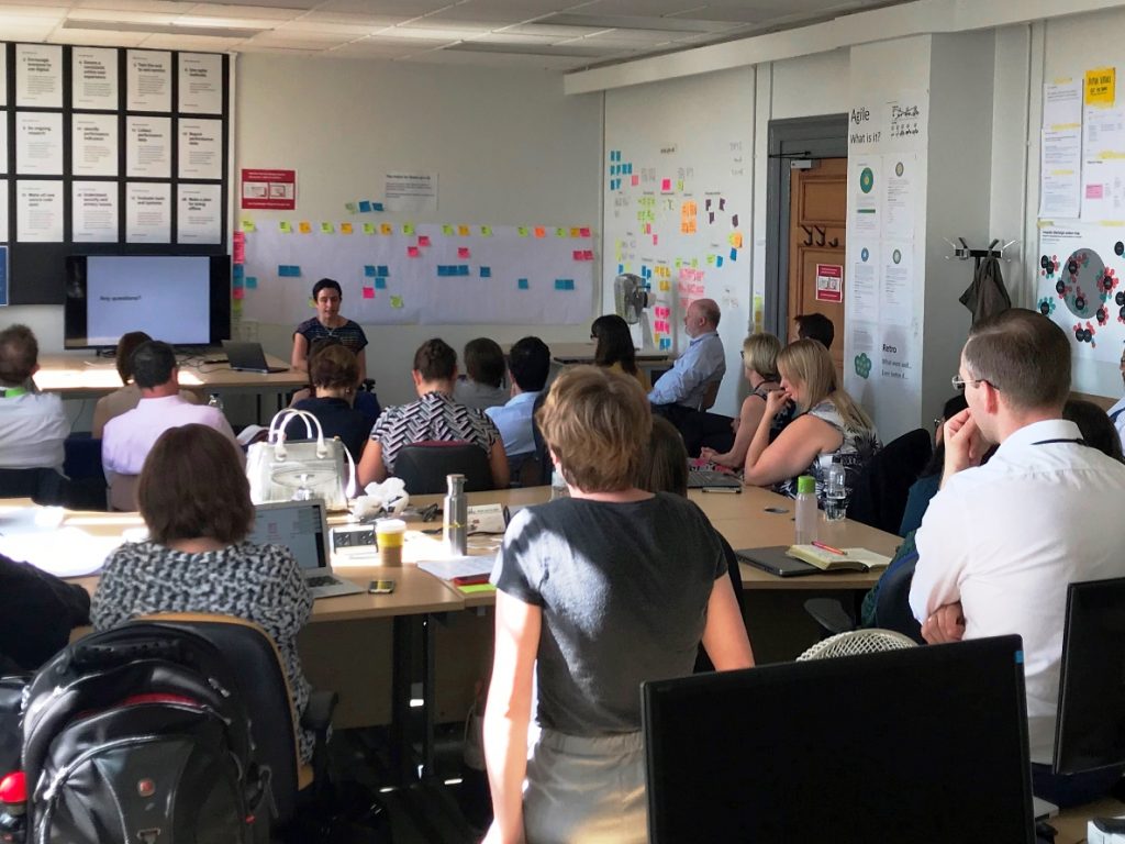 20 people listening to a show and tell presentation in an office setting