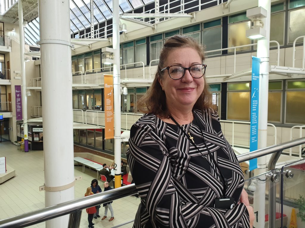 Caroline, content designer standing on the bridge with County Hall atrium in the background